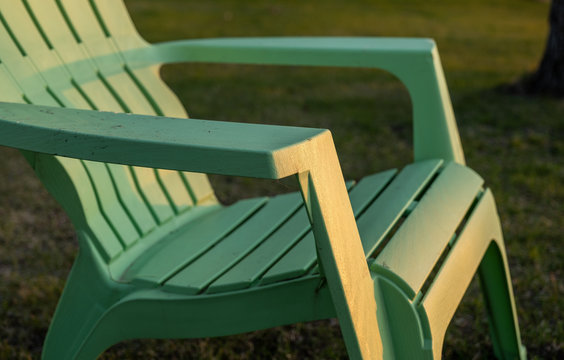 Closeup Of A Lime Green Plastic Resin Adirondack Chair Sitting On The Grass.