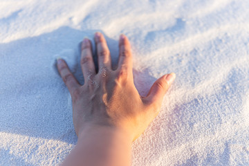 White sands dunes national monument with person's hand closeup on sand texture in New Mexico at sunset light © Kristina Blokhin