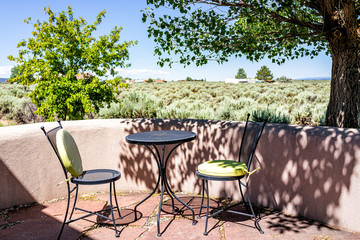 Backyard patio terrace garden with chairs and table in Ranchos de Taos valley and green landscape in summer sunny day and nobody