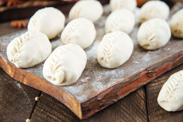Semi-finished manti dumplings on the wooden board