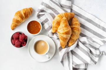 Freshly baked croissants with berries, homemade jam and aromatic coffee for Breakfast on a grey table, top view. Concept of healthy and delicious food.