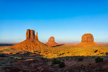 Fototapeta na wymiar Wide angle view of famous buttes and horizon in Monument Valley at sunset vibrant colorful light in Arizona with orange rocks