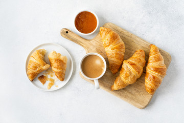 Freshly baked croissants with berries, homemade jam and aromatic coffee for Breakfast on a grey table, top view. Concept of healthy and delicious food.