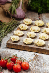 Semi-finished pelmeni dumplings on wooden board