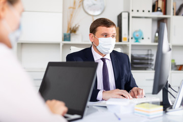 Businessman in face mask working on laptop