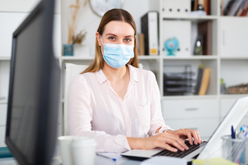 Fototapeta na wymiar Woman in protective face mask working at office