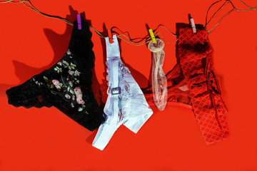 a card for Valentine's Day. women's underpants and condom sit on a red background