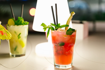 Two crystal glasses with red and yellow cocktails at night