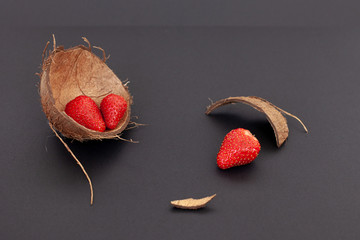 Red strawberries are in the  coconut shell and on a black background, isolated
