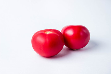 two red tomatoes on a white background.
