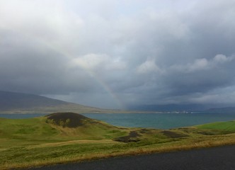 regenbogen regenwolken dunkler himmel meer küste unswetter island