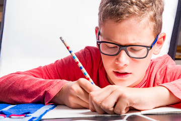 Boy at home school with pencil and math booklet while learning