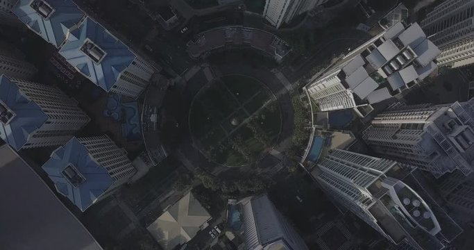 Ungraded, Orbiting ascending aerial flight over roundabout intersection in business district. Drone, 4K.