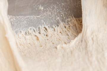 Stretching freshly homemade dough, showing threads