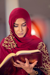 Young muslim woman reading Quran in the mosque and sunlight falling from the window