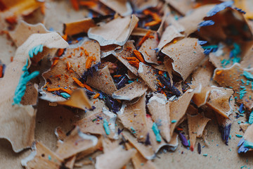 background for art workshop: shavings from sharpening colored pencils lying on a craft paper background with space for your text or advertising