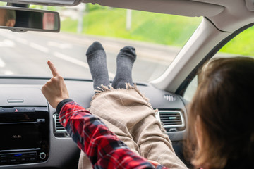 Woman passenger legs in socks wrapped in a plaid on car dashboard while travel on the highway. Freedom  concept.