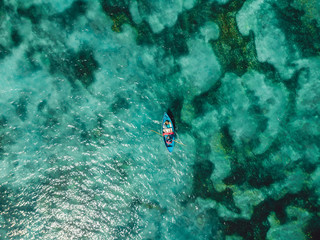 Turquoise ocean water and fisherman on boat, aerial view