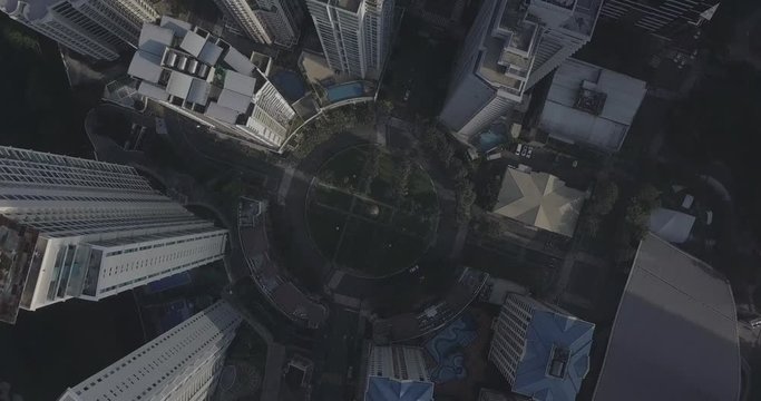 Ungraded, Orbiting descending aerial flight towards roundabout intersection in business district. Drone, 4K.