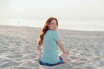 Young woman sitting on a beach looking back