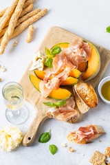 Fresh melon with prosciutto and basil. Antipasti, Italian food. Top view on white stone table with copy space for your text