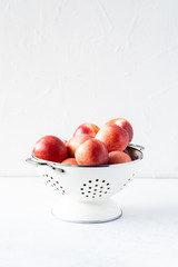 Fresh peaches and nectarines for a delicious Breakfast in a white iron bowl on a white background. The concept of delicious and healthy food. Copy space.