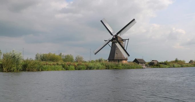 Old windmill spinning in the wind by a dutch canal