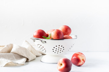 Fresh peaches and nectarines for a delicious Breakfast in a white iron bowl on a white background. The concept of delicious and healthy food. Copy space.