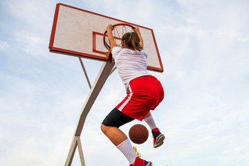 Females playing basketball on street court. Woman streetball player making slam dunk in a...
