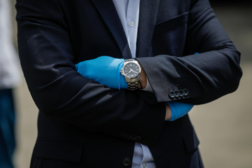 Details with the hands in gloves and watch of a wealthy businessman during the covid-19 outbreak.