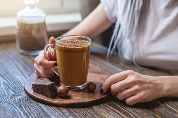 Woman is holding a transparent glass with delicious and refreshing whipped coffee. A trendy spectacular drink that can made at home