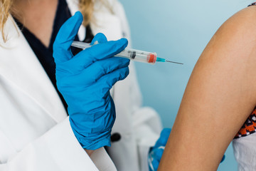 female health care worker administering a shot vaccination for a child