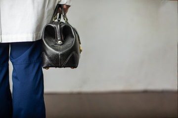 Female physician holding a black leather doctor's bag heading to the office to practice medicine
