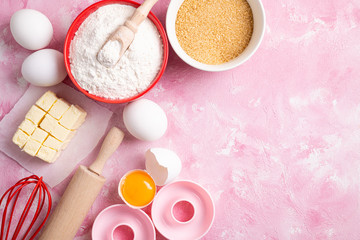 Fototapeta na wymiar Ingredients for baking flour, eggs, butter, sugar on pink background flat lay. Baking or cooking cakes or donuts. Baking background. Top view, copy space