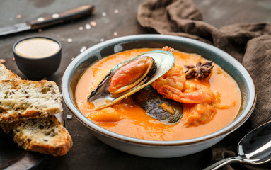 Tomato gazpacho soup with mussels, squid, shrimp in bowl over dark wooden background with napkin. Seafood, healthy food, close up