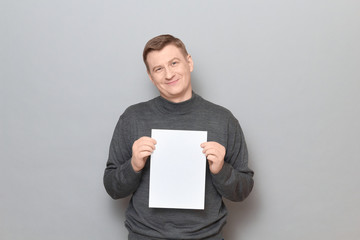 Portrait of happy man holding white blank paper sheet in hands