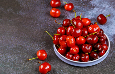 Fresh cherry on plate on dark background.