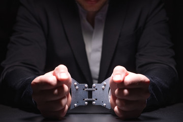 Handcuffed hands in a dark room
