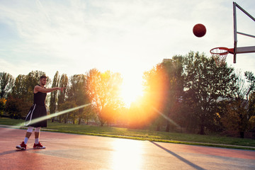 Young man jumping and making a fantastic slam dunk playing streetball, basketball. Urban authentic.