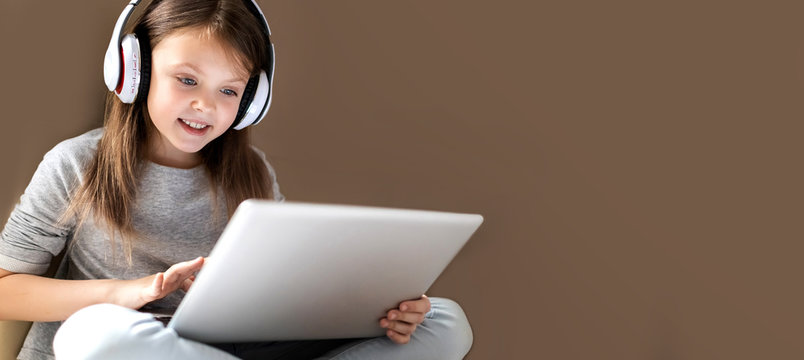 Kids distance learning. Cute clever little girl using laptop at home. Education, online study, home studying, schoolgirl children lifestyle concept. Horisontal banner. Copy space for text.