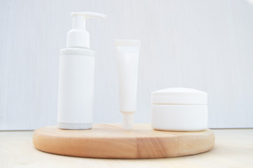 Isolated SPA cosmetic products, a white tube, a jar with a dispenser and a cream jar on wooden board on a white background. Branding layout, mock up.
