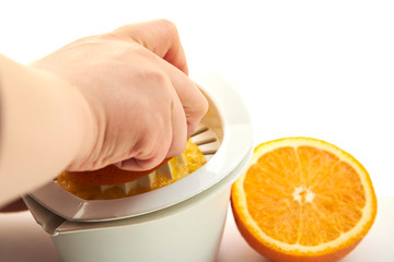 Making orange juice using a manual juicer on a white background.