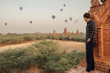 Man looking baloons over the temples at sunrise in Bagan, Myanmar