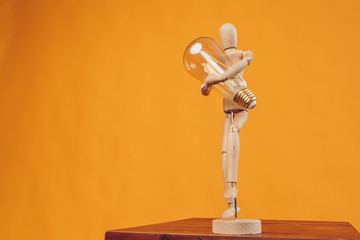 light bulb in the hands of a toy on a yellow background