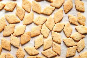 Freshly baked cheese cookies. Top view of a lot of hot fresh cookies on a baking sheet. Selective soft focus.