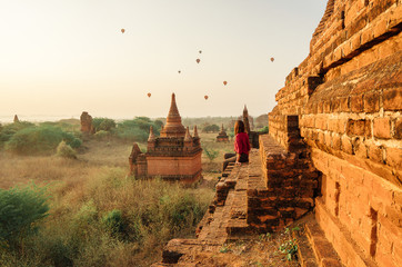 Woman looking baloons over the temples at sunrise in Bagan, Myanmar