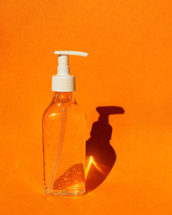 Bottle with gel hand sanitizer. Orange colorful background. Means of hand disinfection during a pandemic Coronavirus