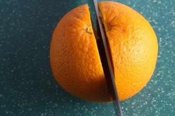 cutted in two halves orange fruit by knife on green board