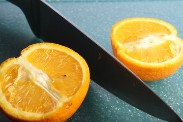 cutted in two halves orange fruit by knife on green board