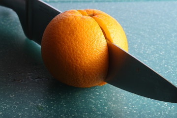 cutted in two halves orange fruit by knife on green board